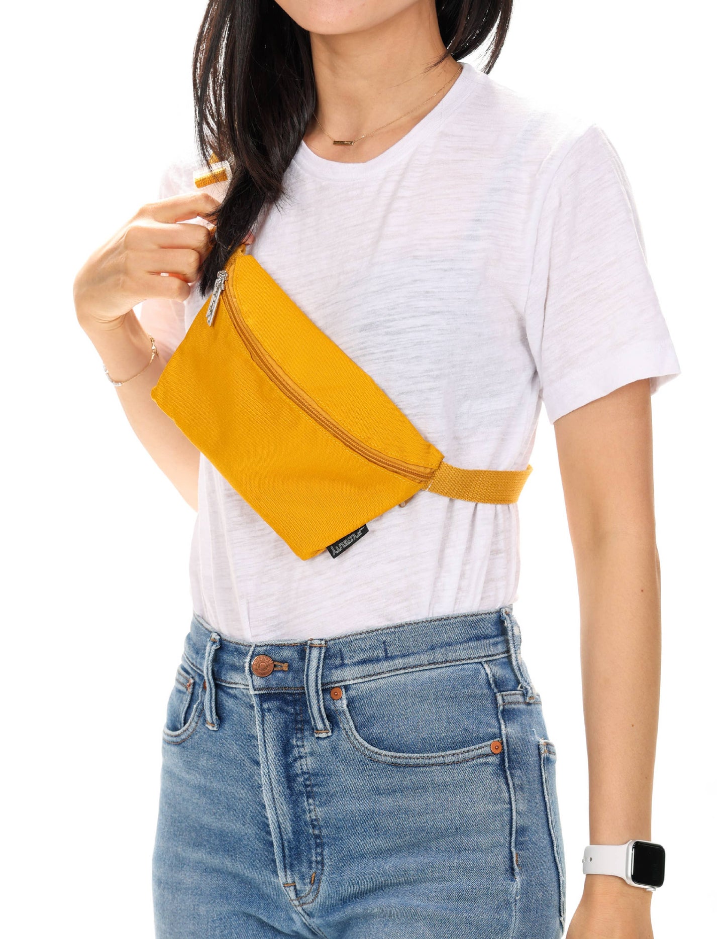 Person wearing a mustard yellow waist bag on a white background