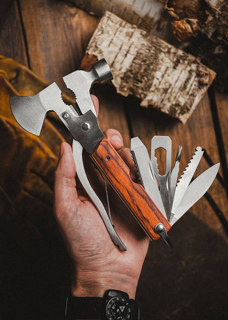 Multitool with wooden handle held by a hand on a wooden background