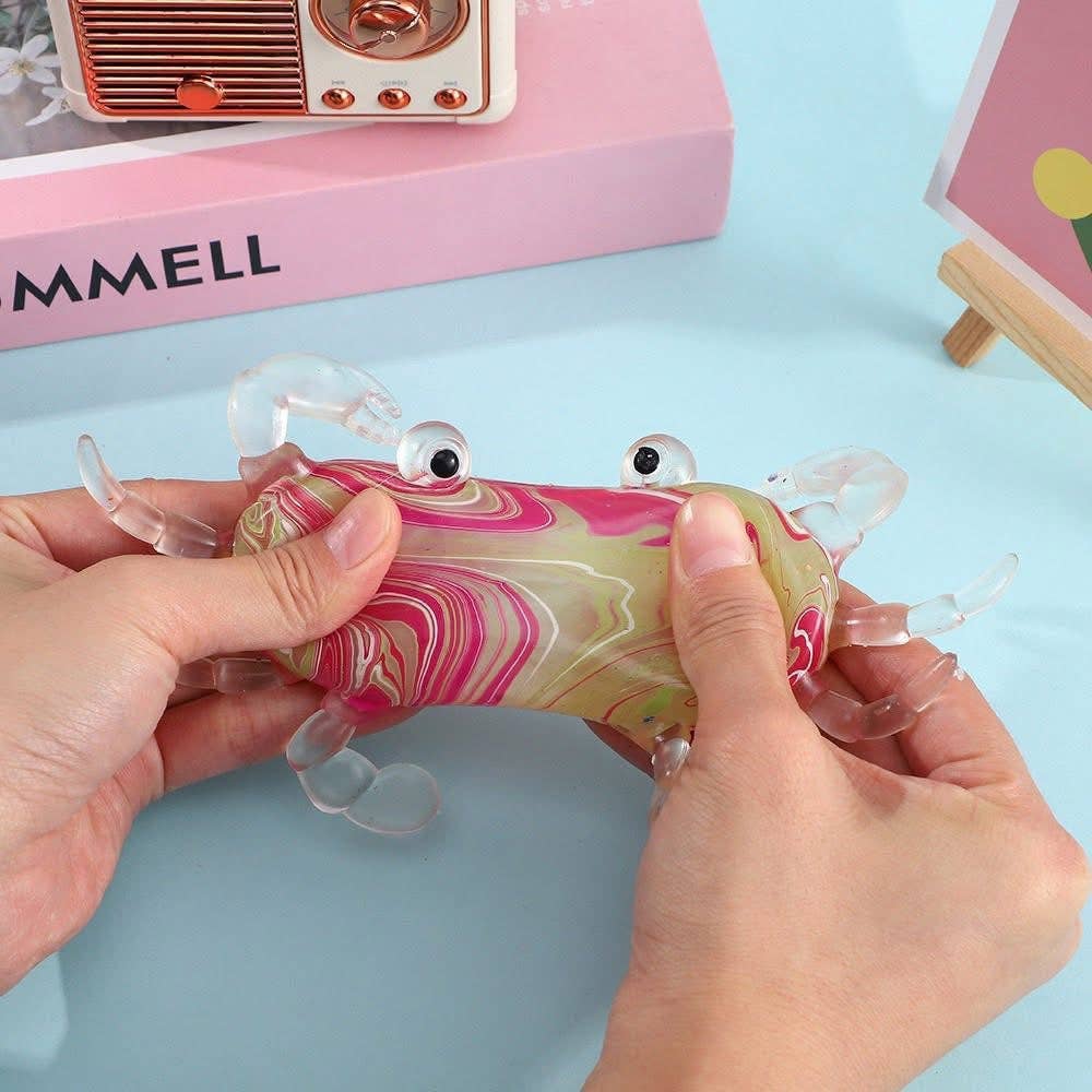 Marbled pink and yellow crab toy held by hands on a light blue background