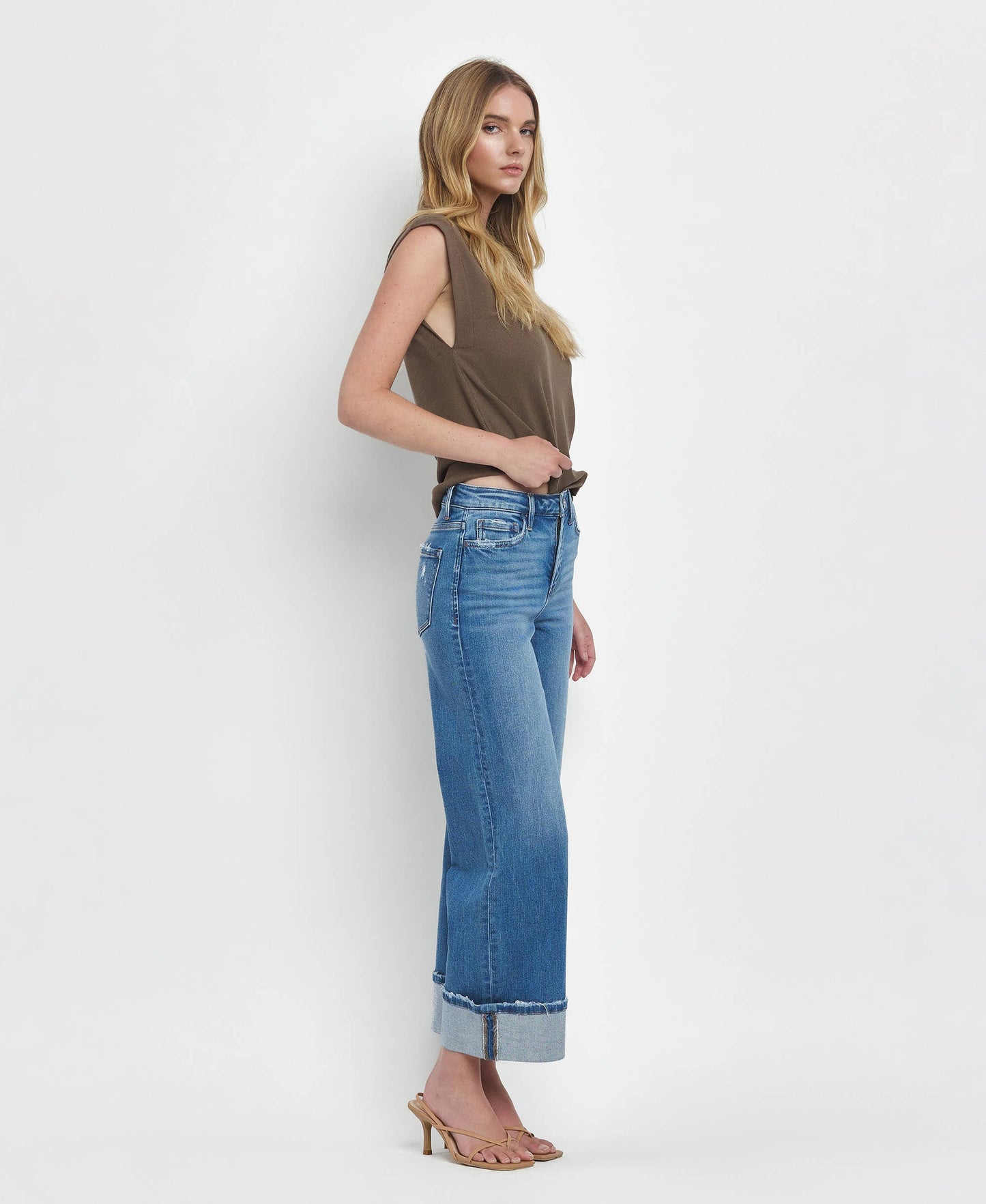 Woman wearing a sleeveless top and blue jeans on a white background