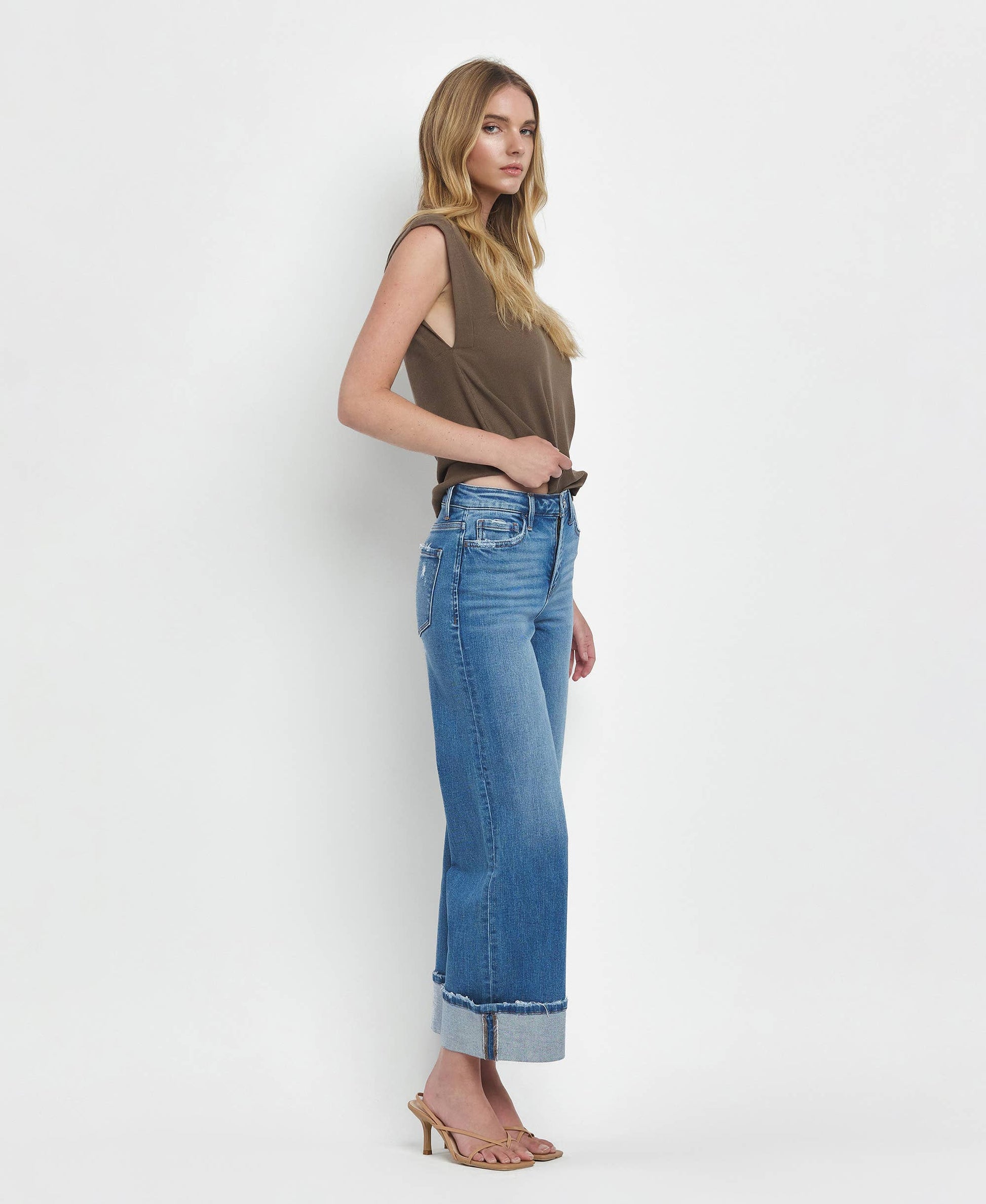 Woman wearing a sleeveless top and blue jeans on a white background