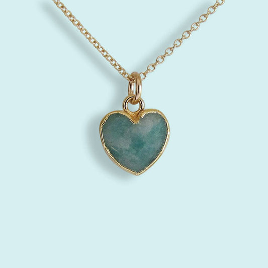 Heart-shaped pendant necklace with gold frame on a light blue background