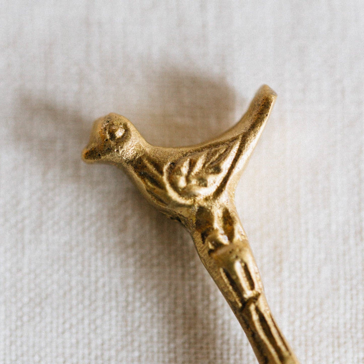 Gold bird-shaped decorative item on a white fabric background