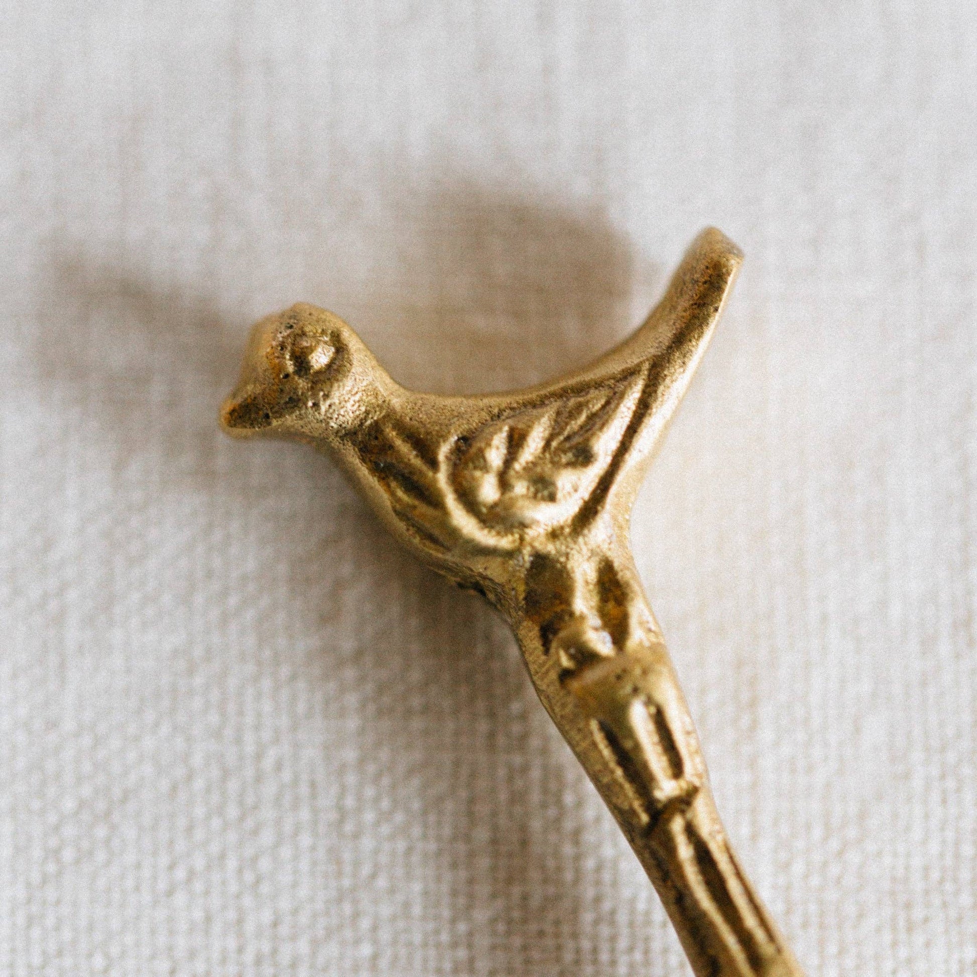 Gold bird-shaped decorative item on a white fabric background