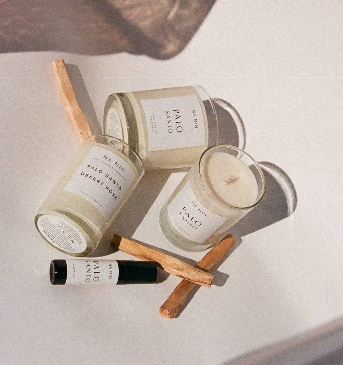 Candle and essential oil bottles with wooden sticks on a light surface
