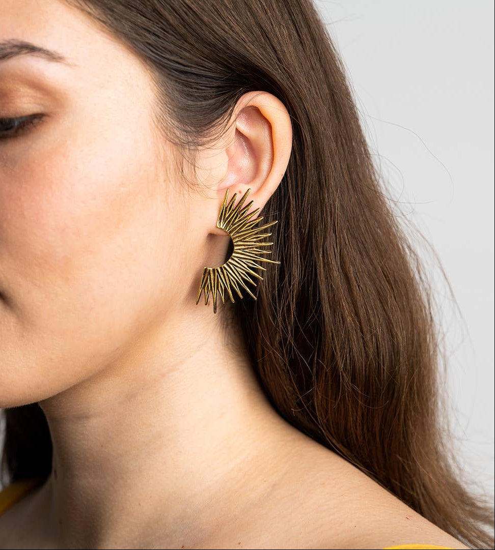 Close-up of a woman wearing a gold earring with a white background
