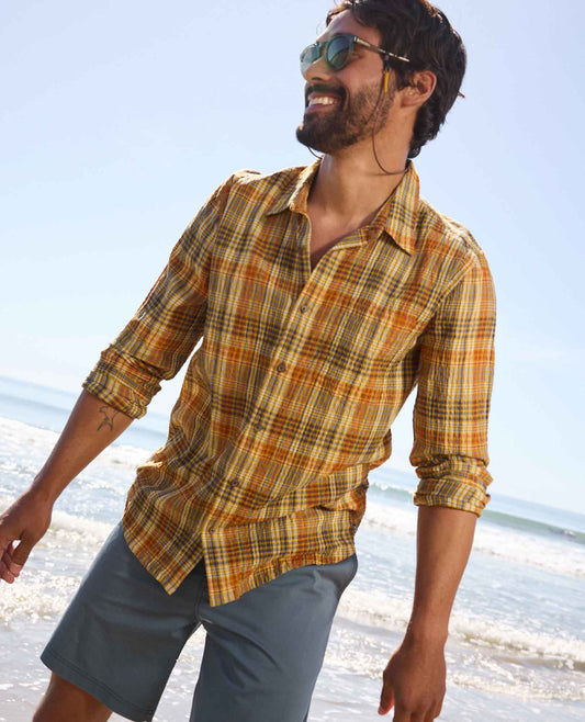 Man wearing a plaid shirt and sunglasses on a beach