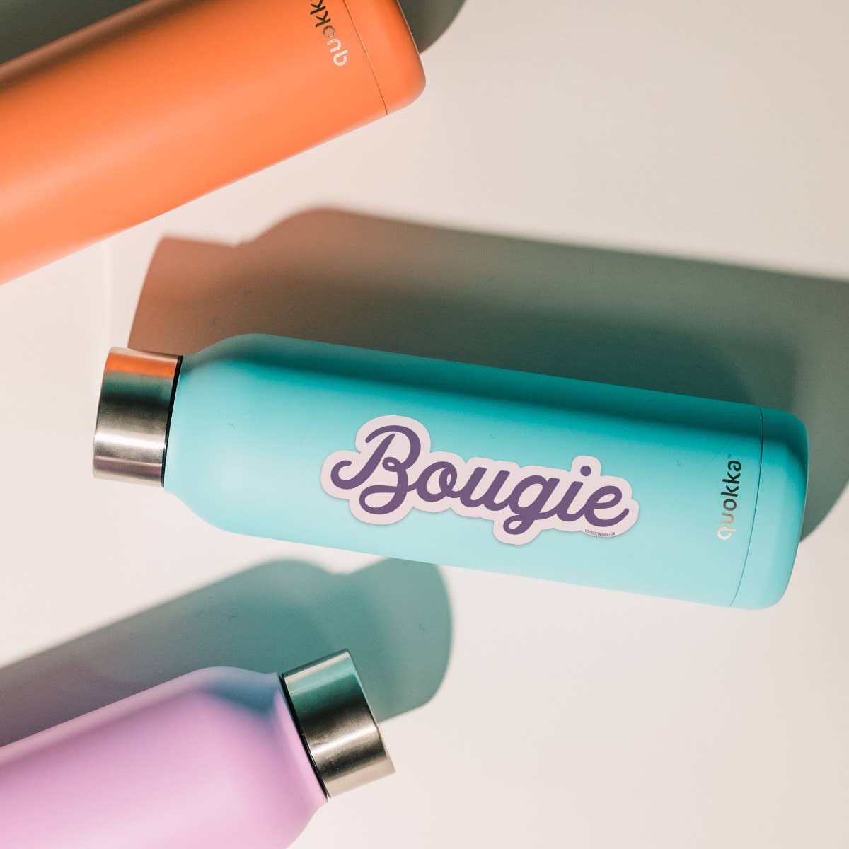 Colorful water bottles with 'Bougie' branding on a reflective surface