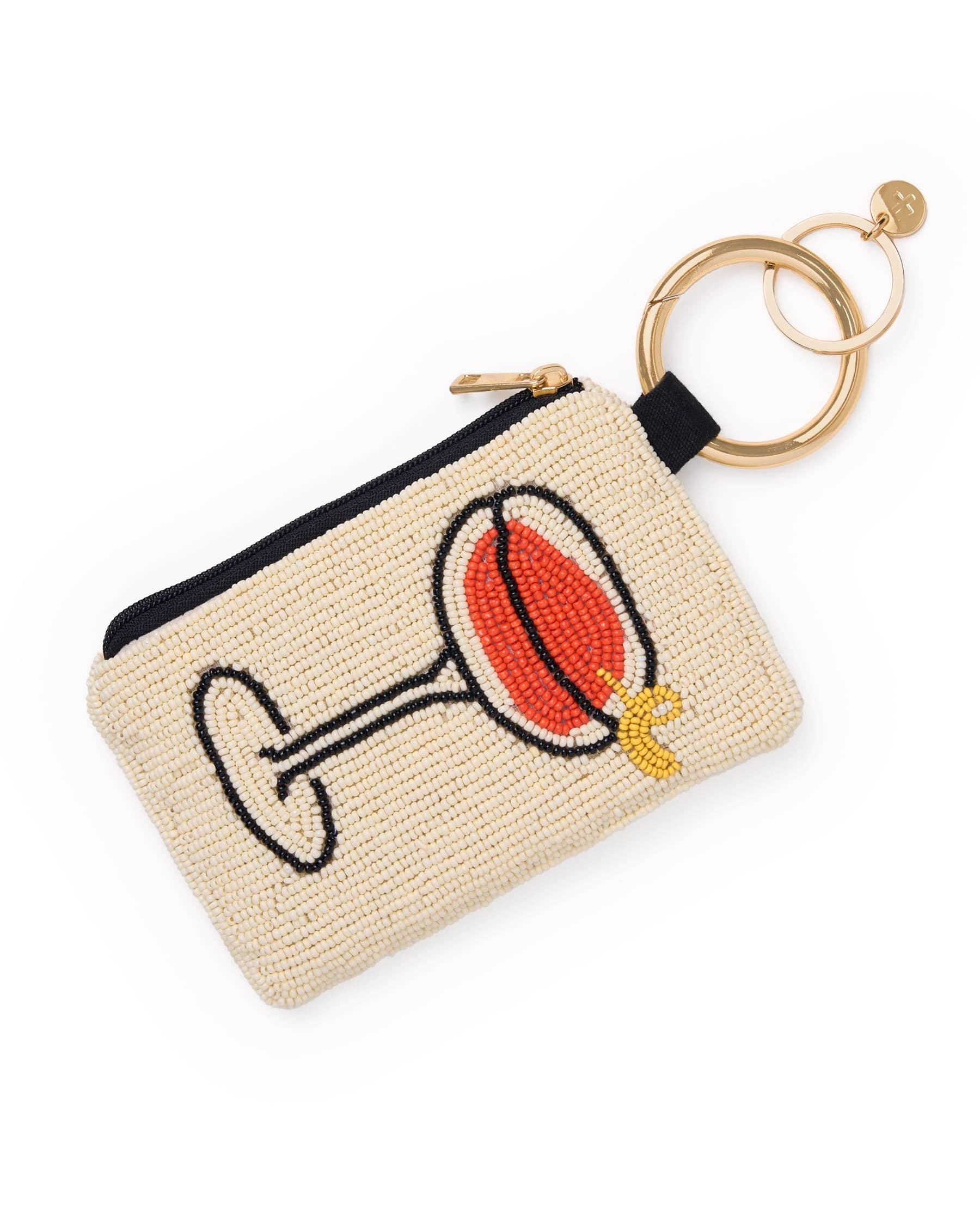 A small woven beige pouch with a black zipper, featuring a beaded cocktail glass design in red, black, white, and gold. It is attached to a gold-tone key ring and keychain, shown on a clean white background.