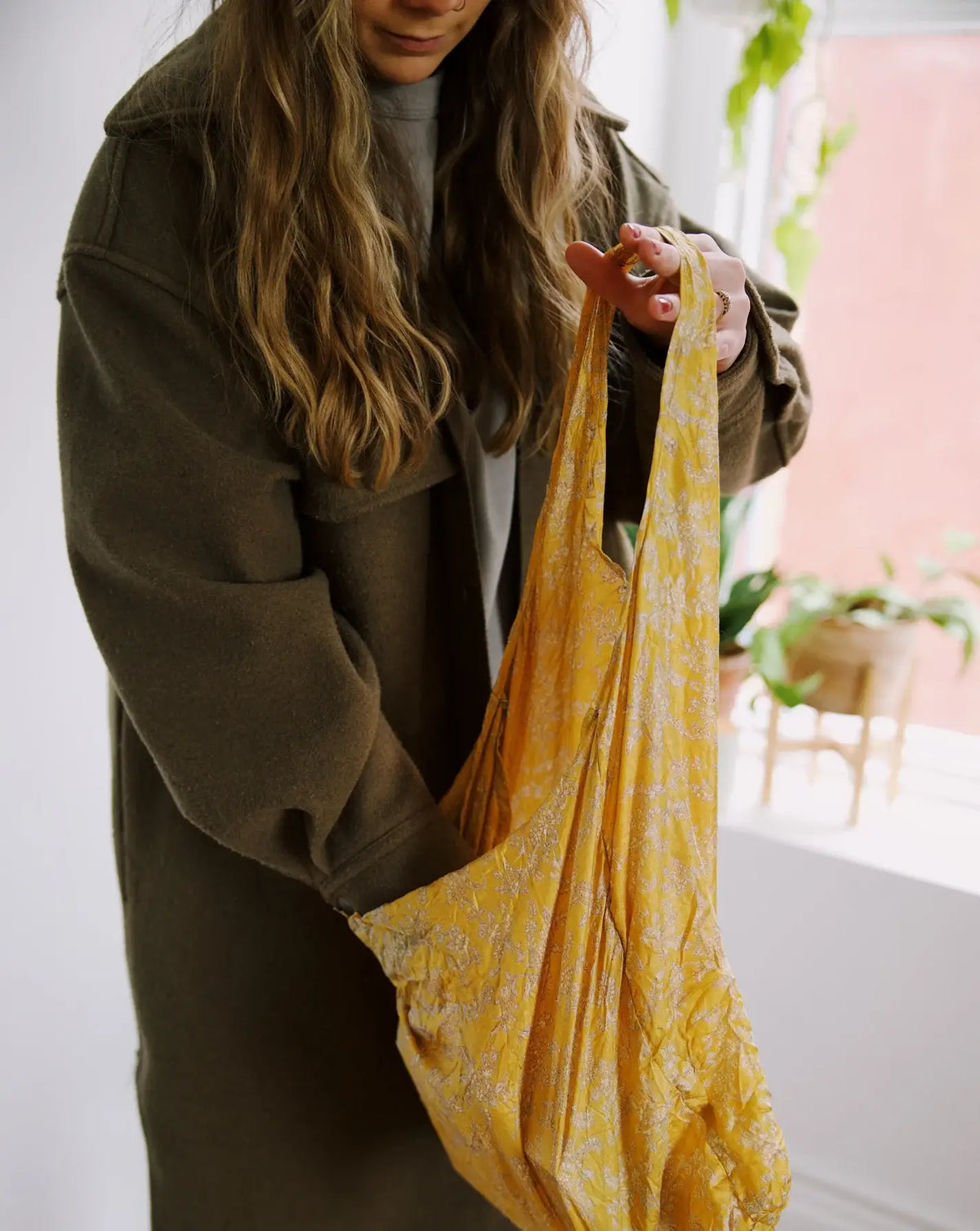 Person holding a yellow floral bag indoors with a blurred background
