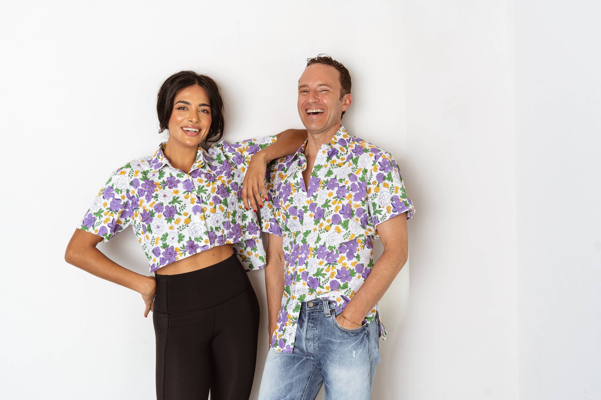 Two people wearing matching floral shirts against a white background