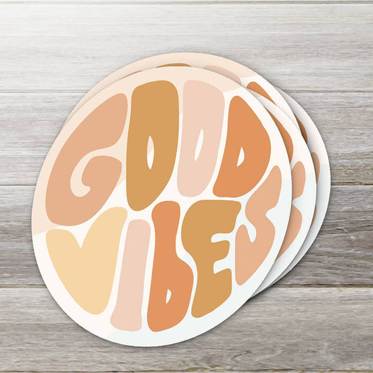 Round sticker with 'Good Vibes' text in pastel colors on a wooden surface