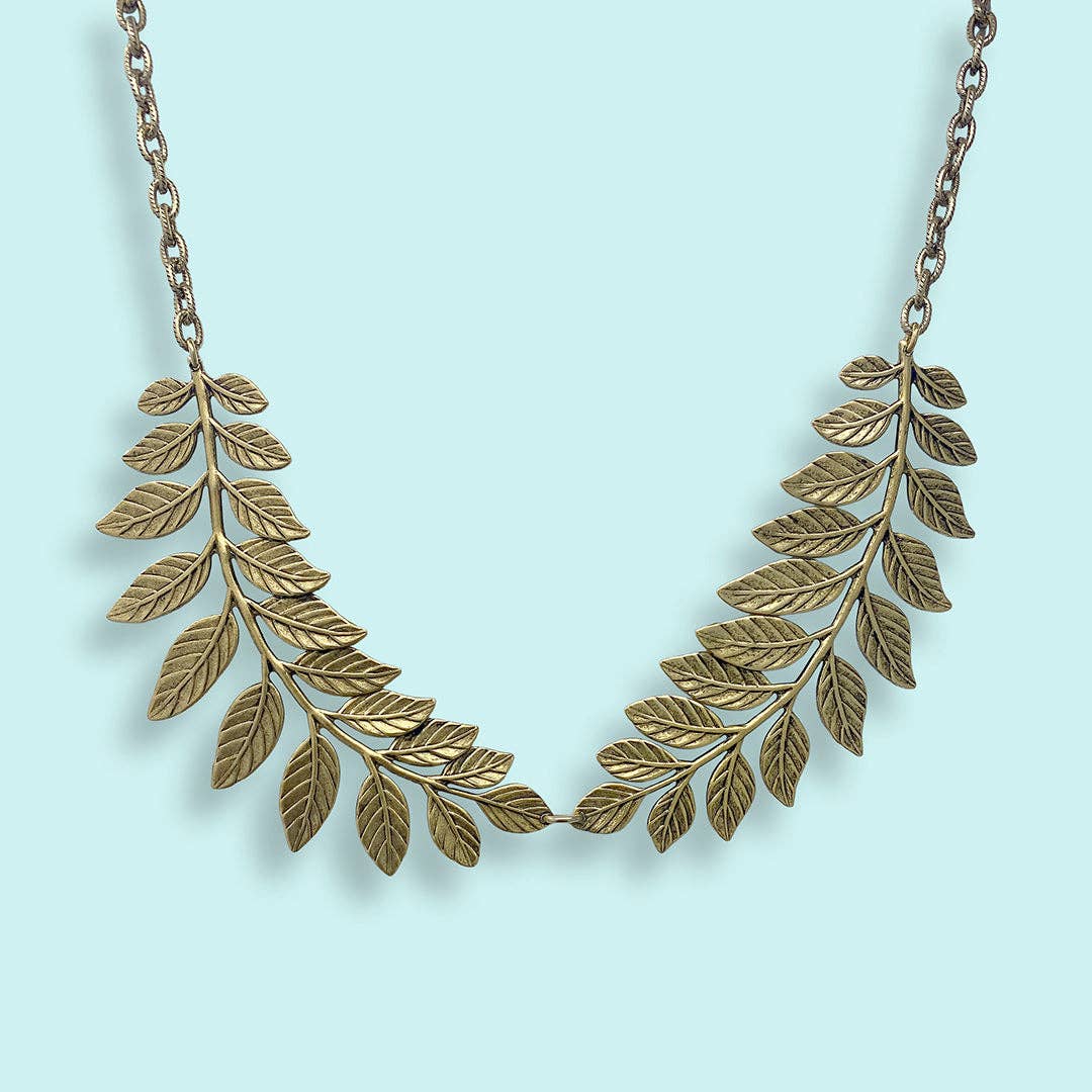 Gold leaf necklace on a light blue background