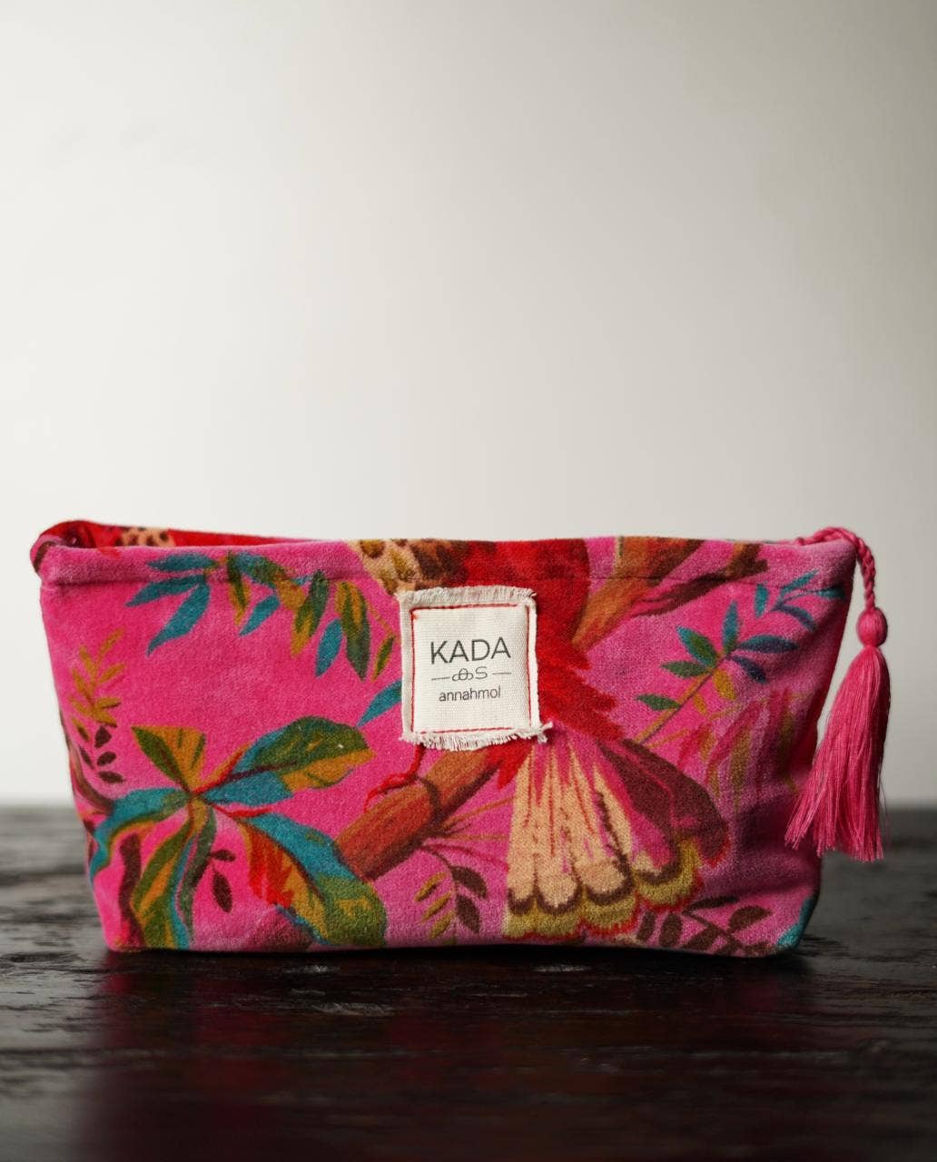 Colorful pouch with floral design and tassel on a wooden surface
