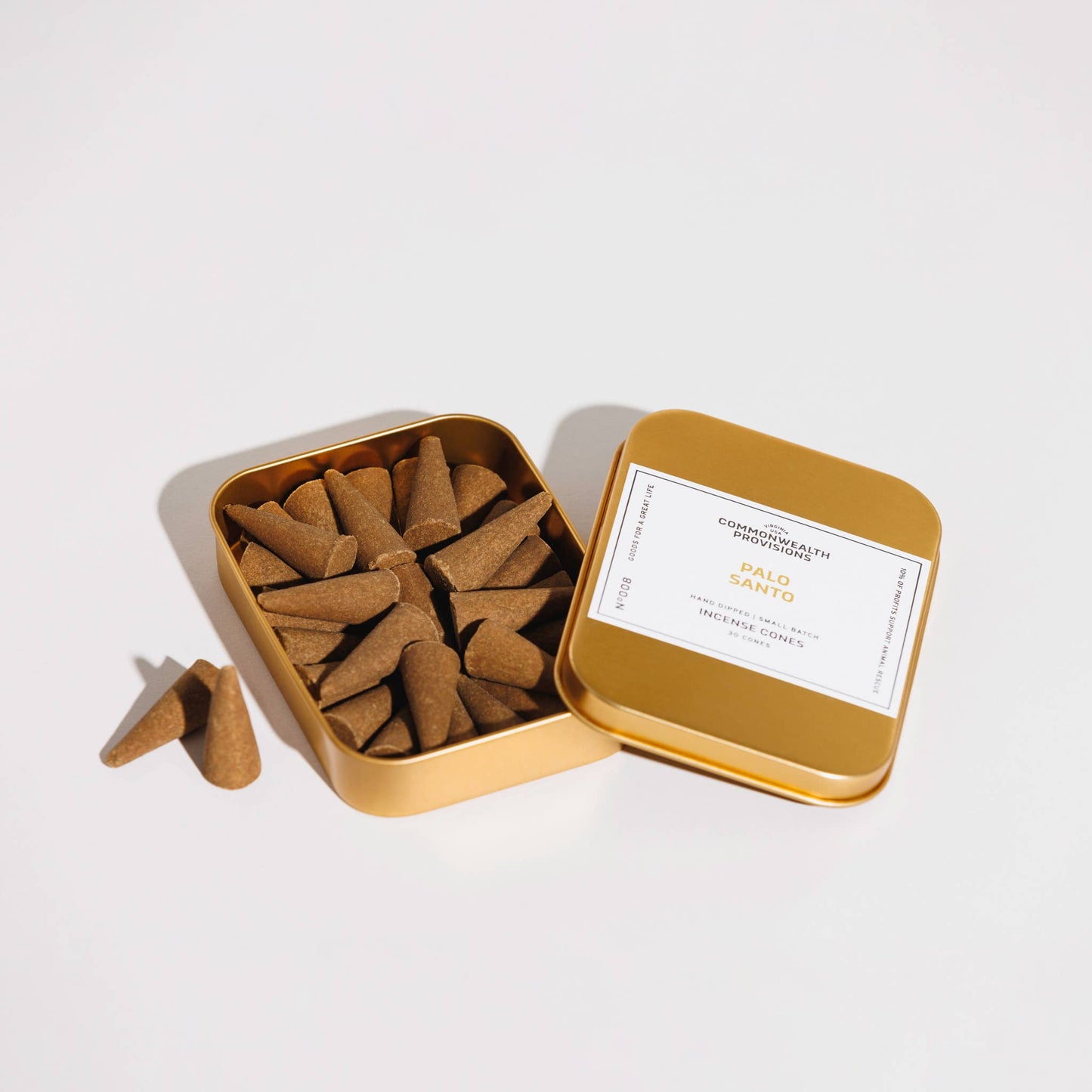 Open gold tin filled with incense cones on a white background