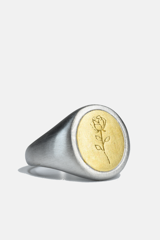 Silver ring with a gold accent featuring an engraved design on a white background