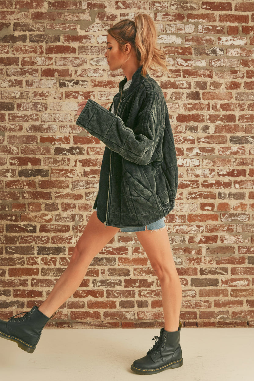 Woman wearing a dark gray jacket and black boots on a beige background