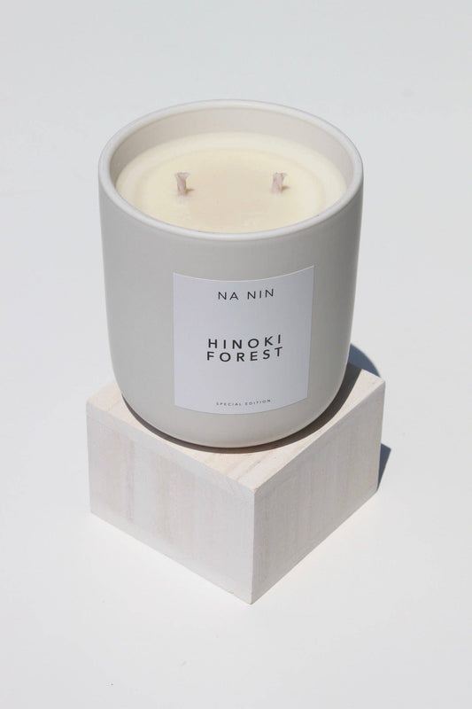 Candle in a gray container labeled 'Hinoki Forest' by 'NA NIN' on a white background