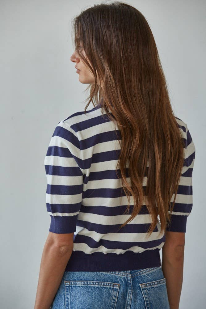 Woman wearing a navy and white striped shirt with blue jeans against a plain background