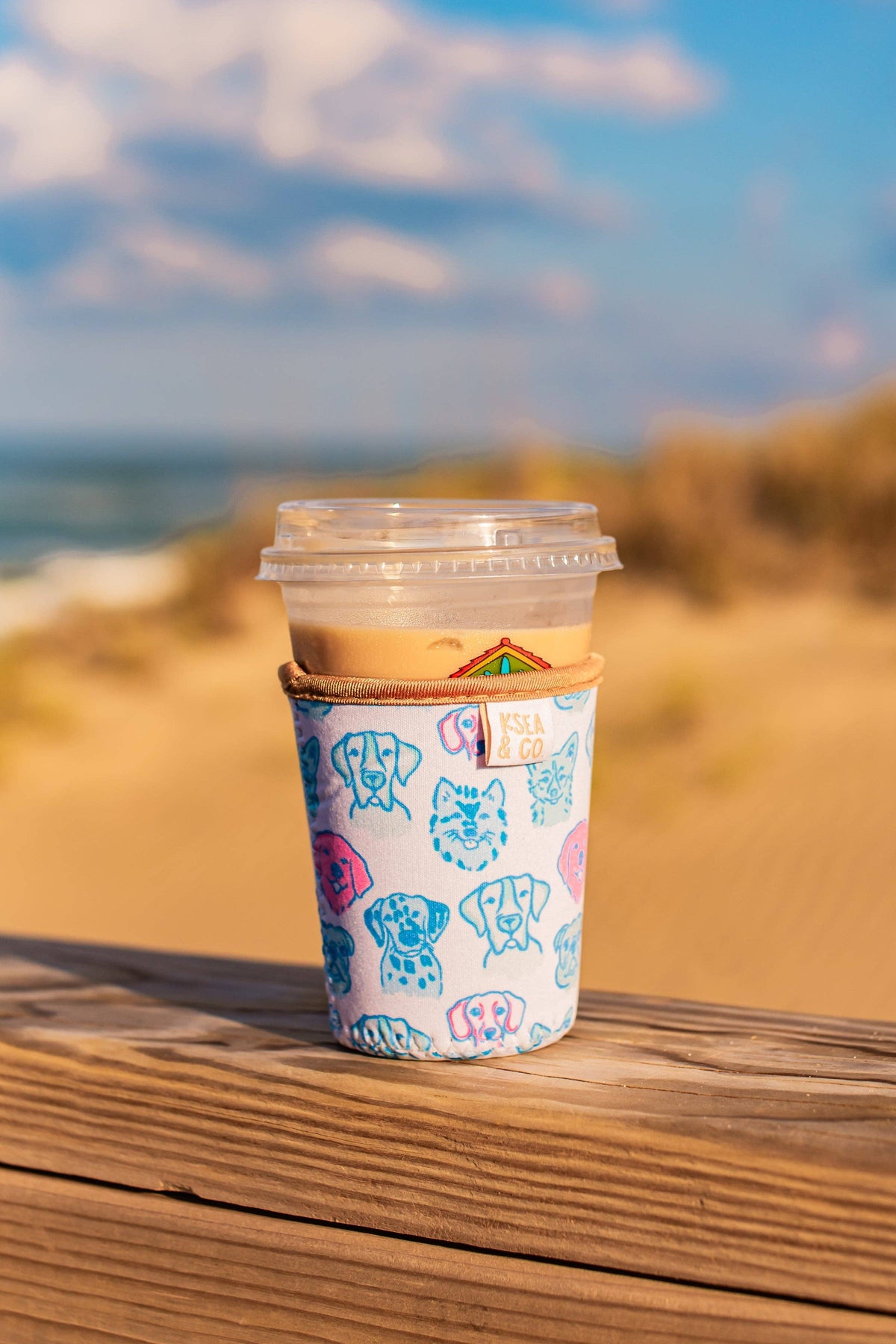Coffee cup with a colorful sleeve on a wooden surface with a beach background