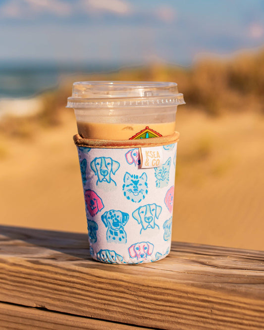 Coffee cup with a colorful sleeve on a wooden surface with a beach background