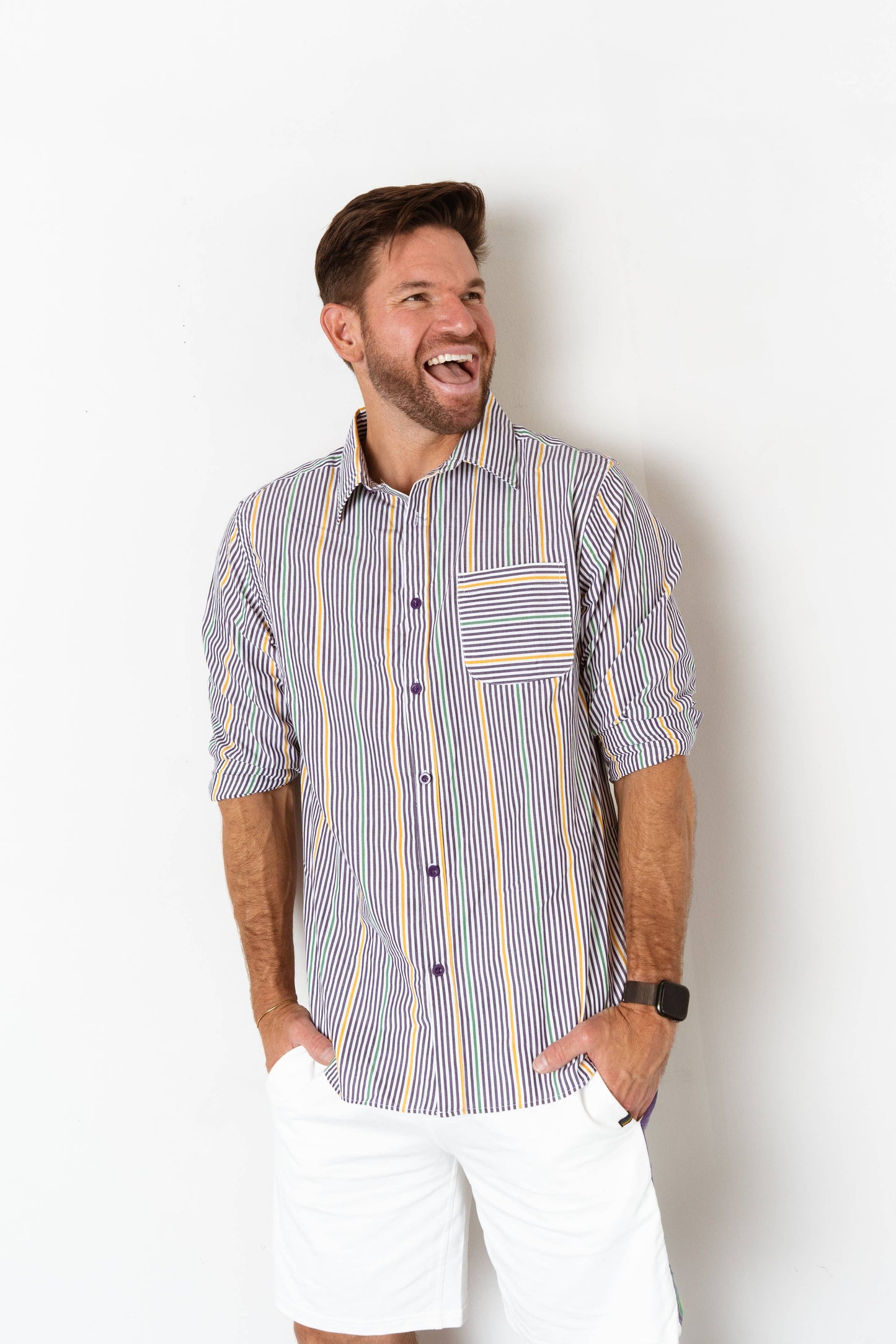 Man wearing a striped shirt and white shorts against a plain background