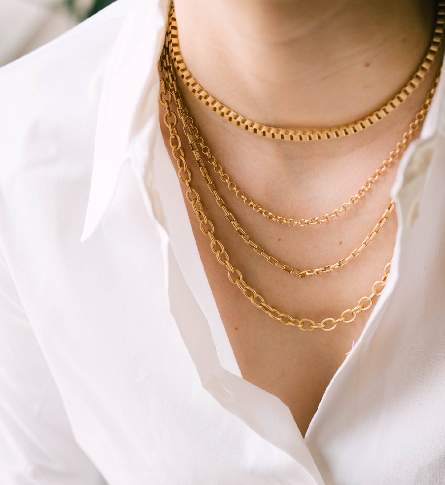 Gold chain necklaces on a person wearing a white shirt