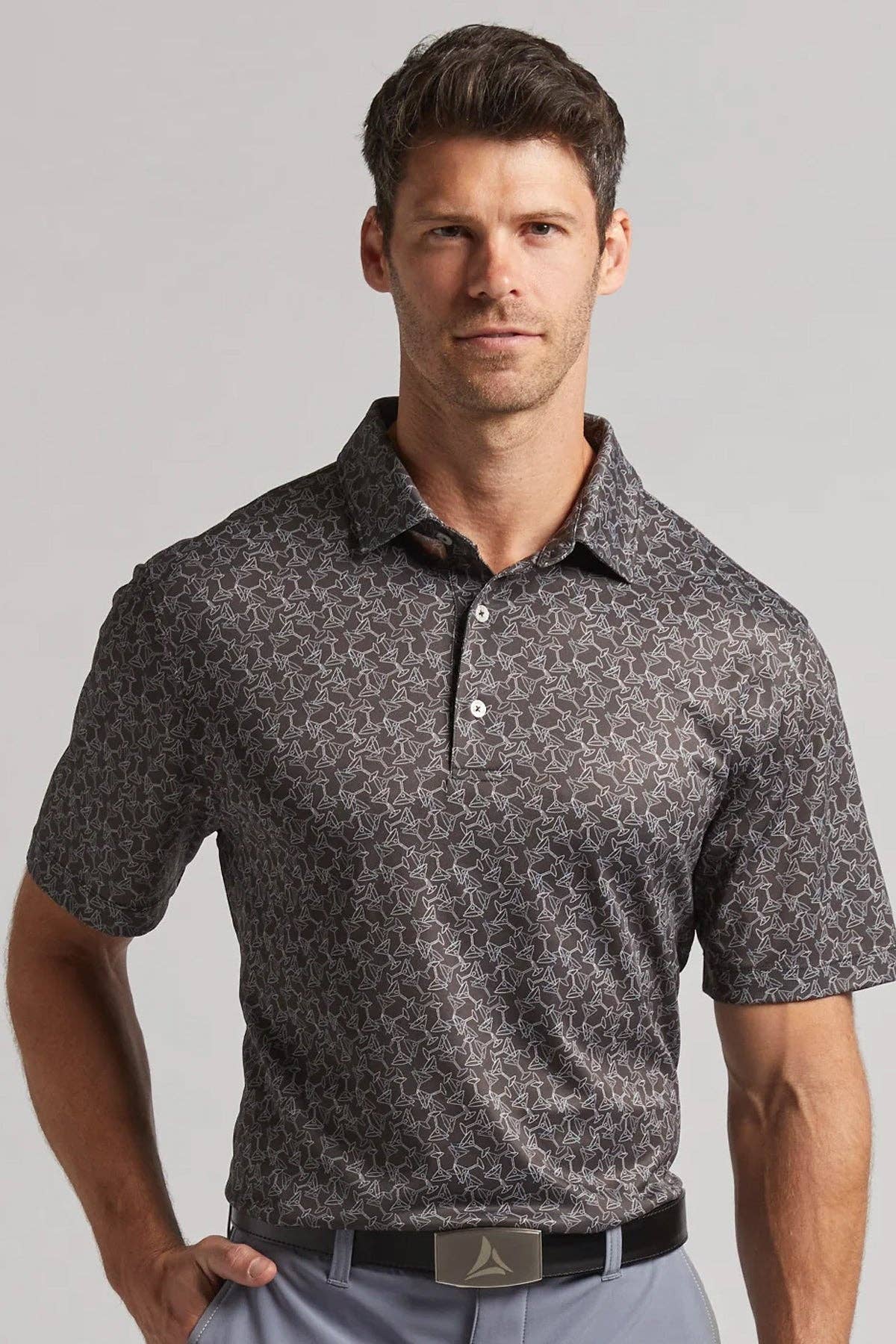 Man wearing a patterned gray polo shirt against a plain background