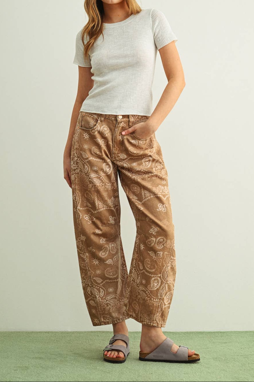 Woman wearing a white t-shirt and brown patterned pants on a light green background