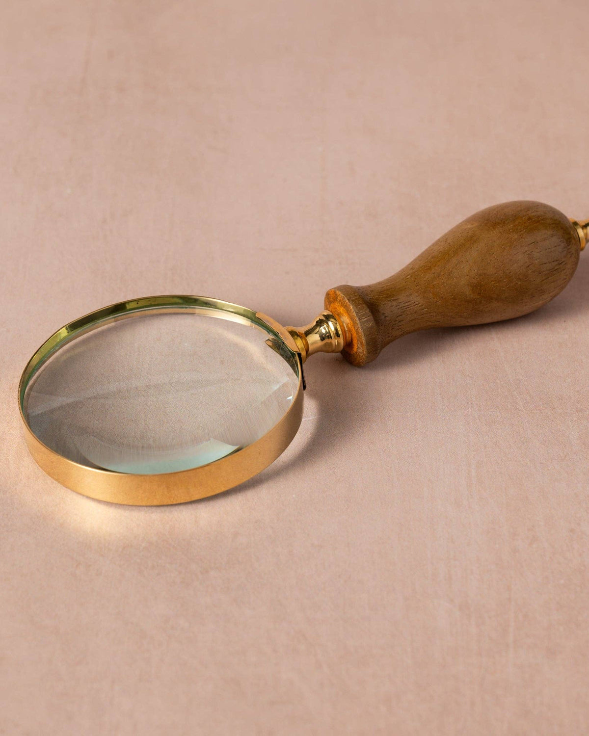 Magnifying glass with wooden handle on a beige background