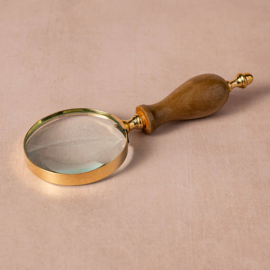 Magnifying glass with wooden handle on a beige background