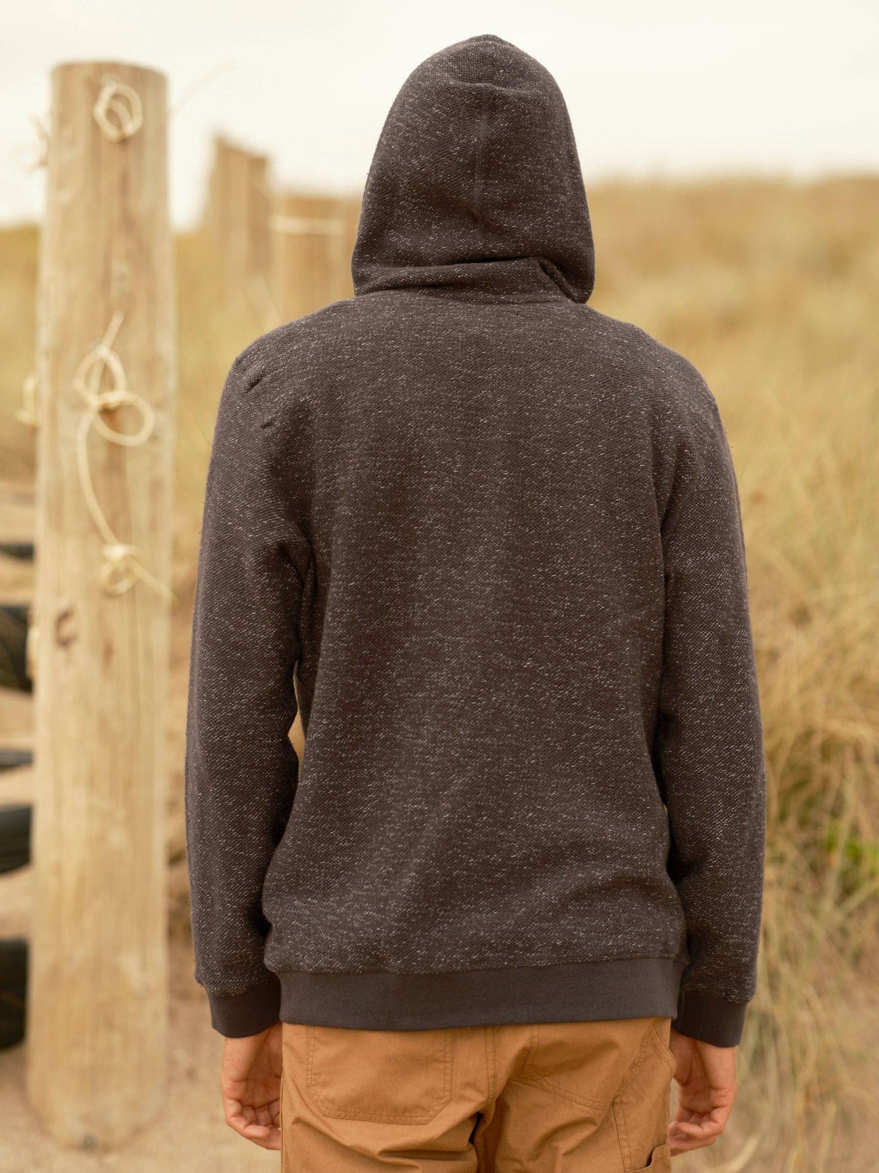 Person wearing a dark hoodie in a desert-like setting