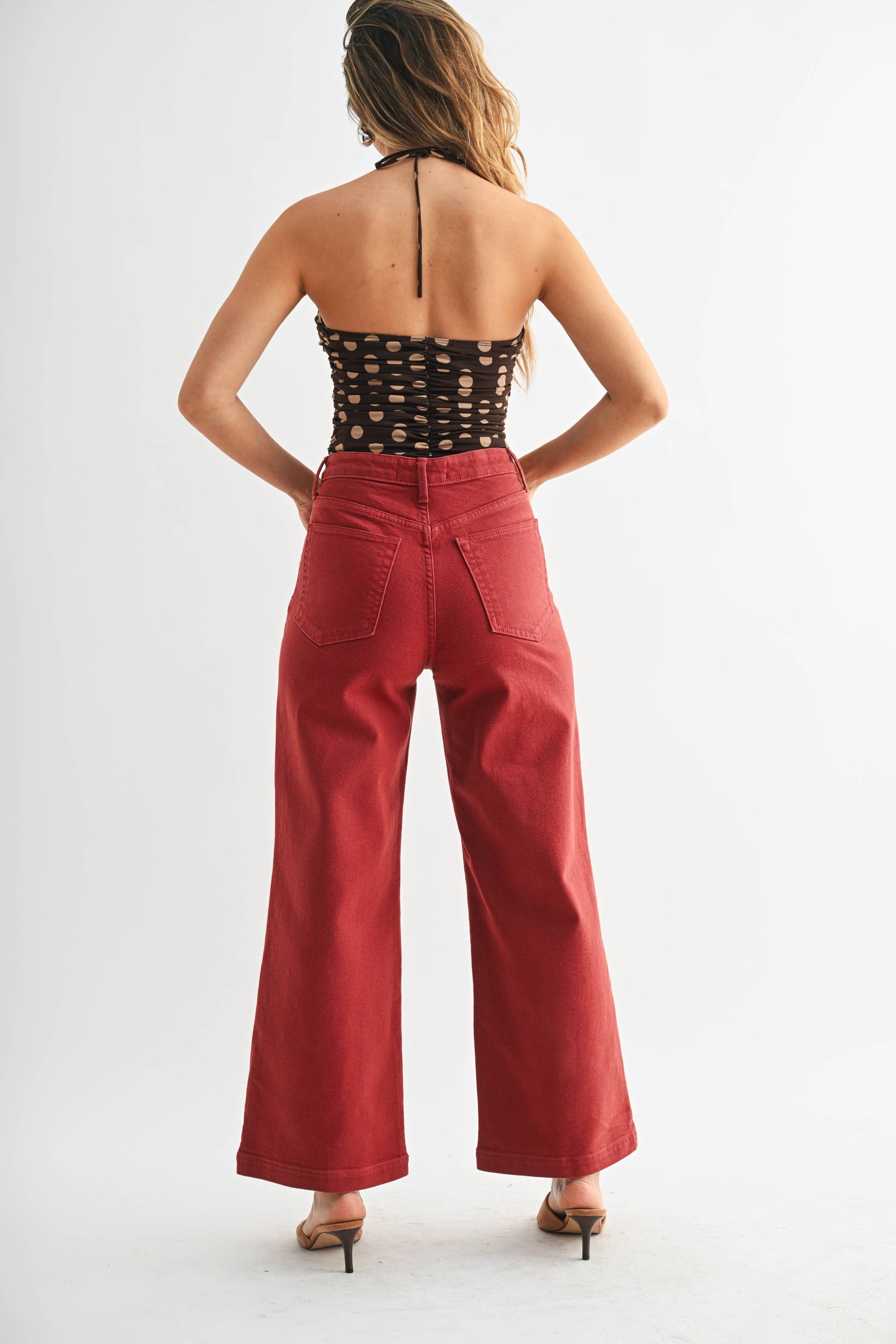 Woman wearing a black lace top and red high-waisted pants on a white background