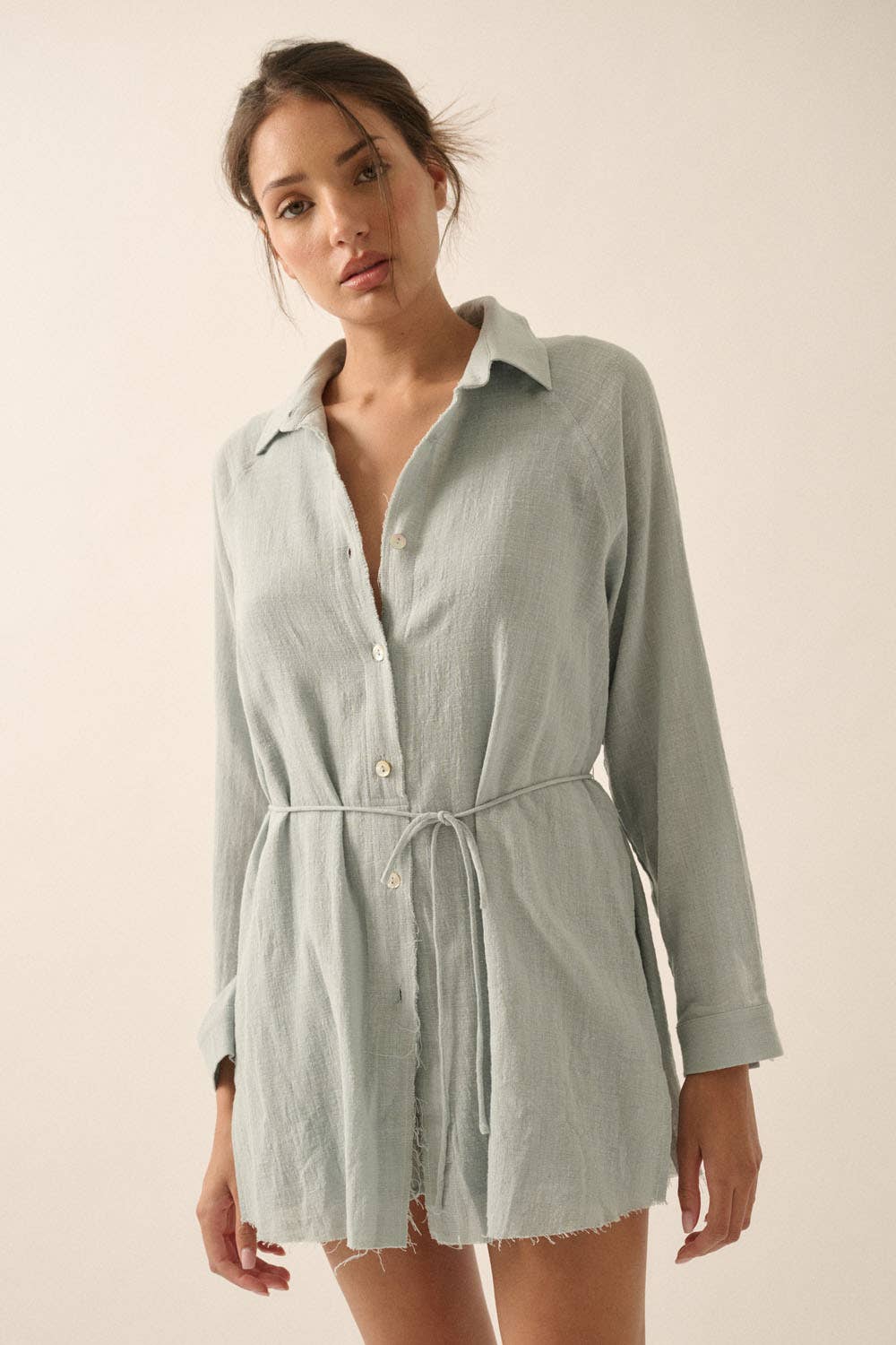 Woman wearing a light blue shirt dress against a plain background