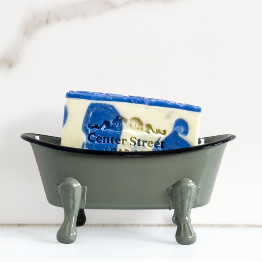 Soap dish shaped like a bathtub with a bar of soap on a white background