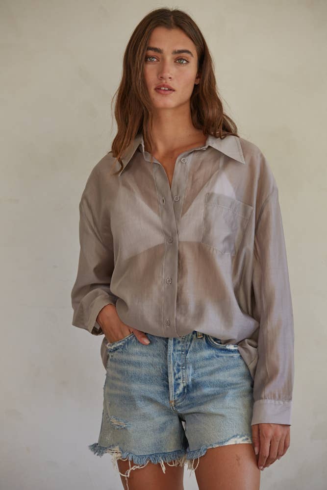 Woman wearing a beige shirt and denim shorts against a plain background