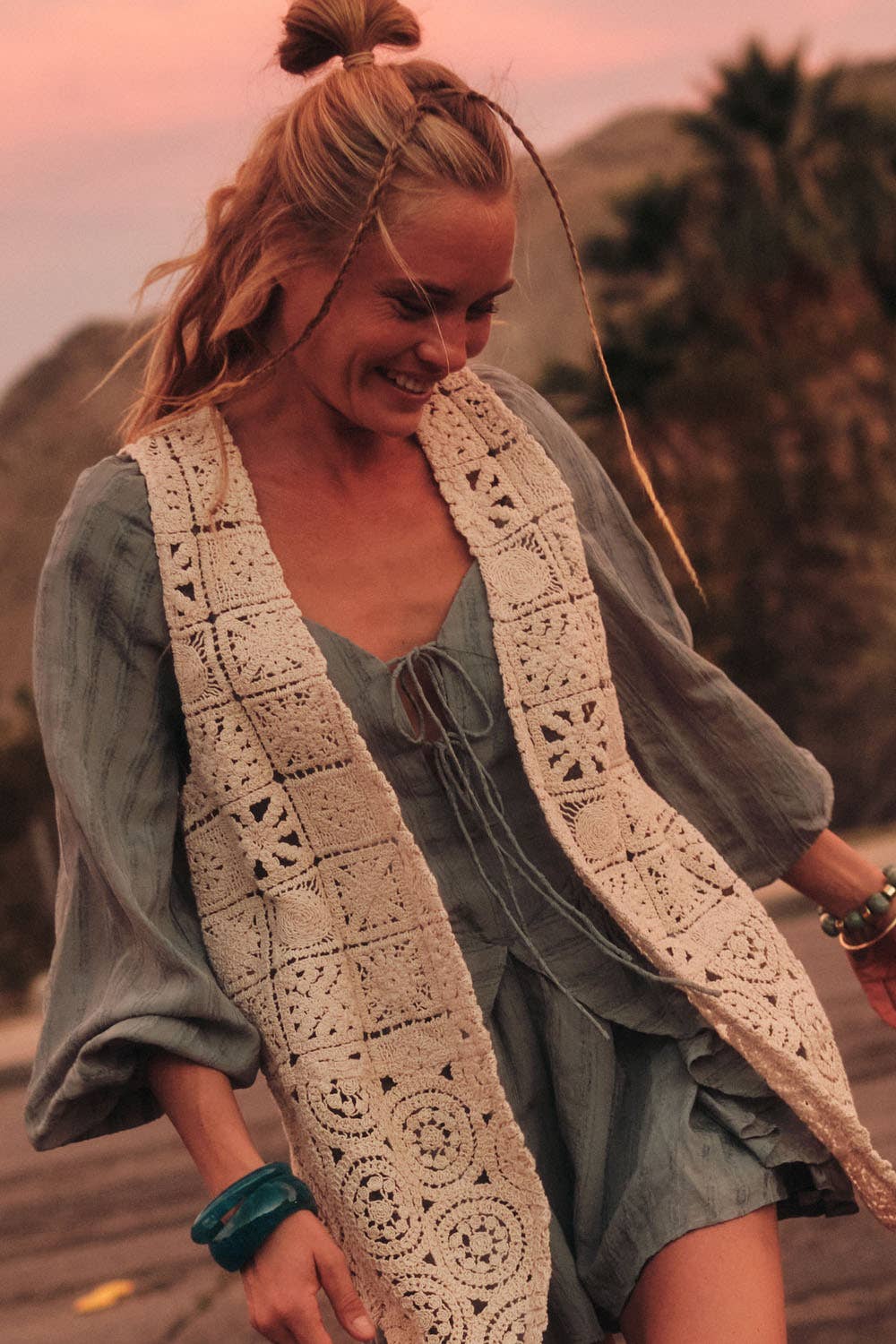 Woman wearing a crochet vest outdoors with a blurred natural background