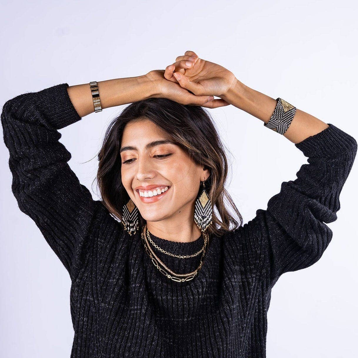Woman wearing a dark gray sweater with jewelry on a white background