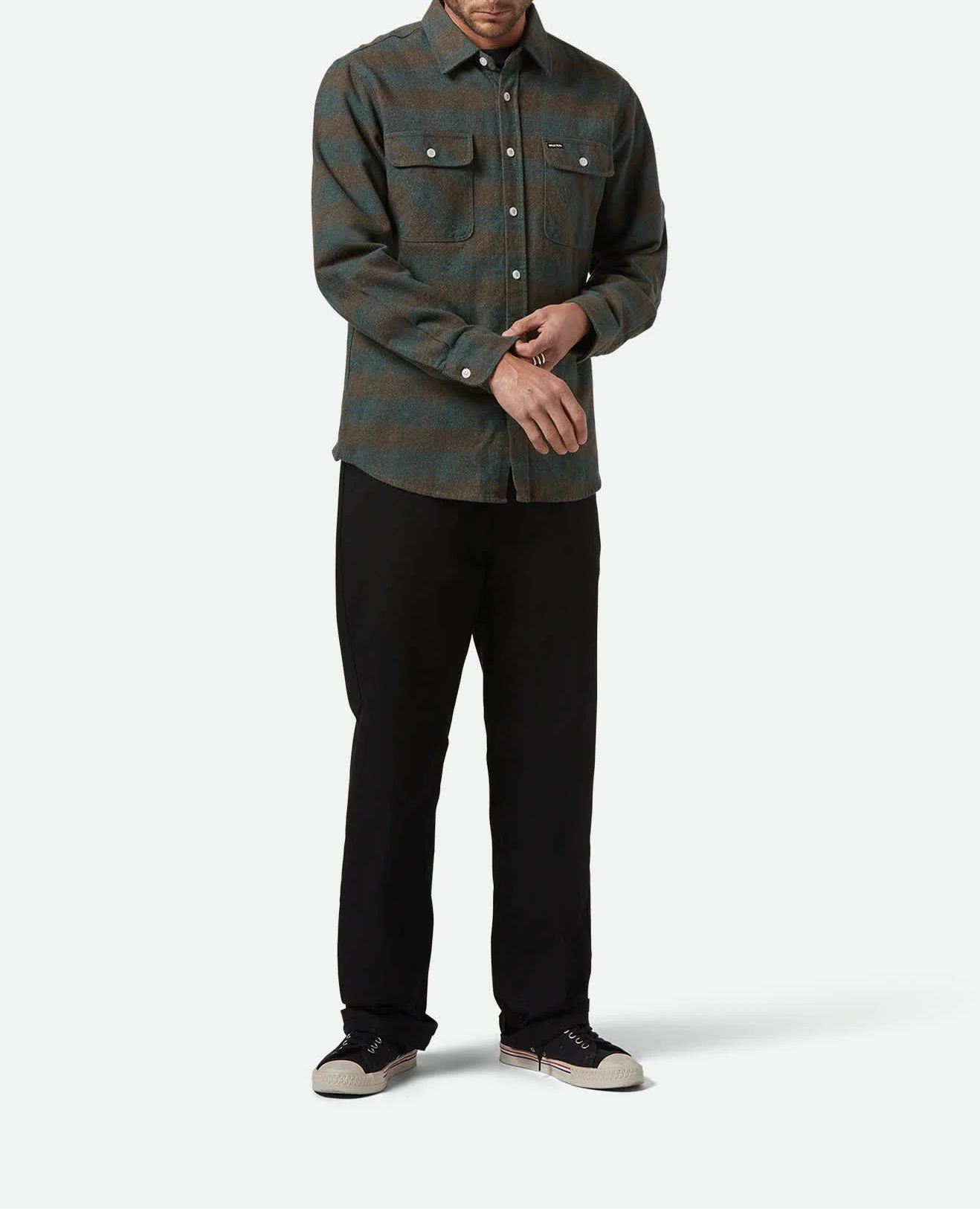Man wearing a green plaid shirt and black pants on a white background