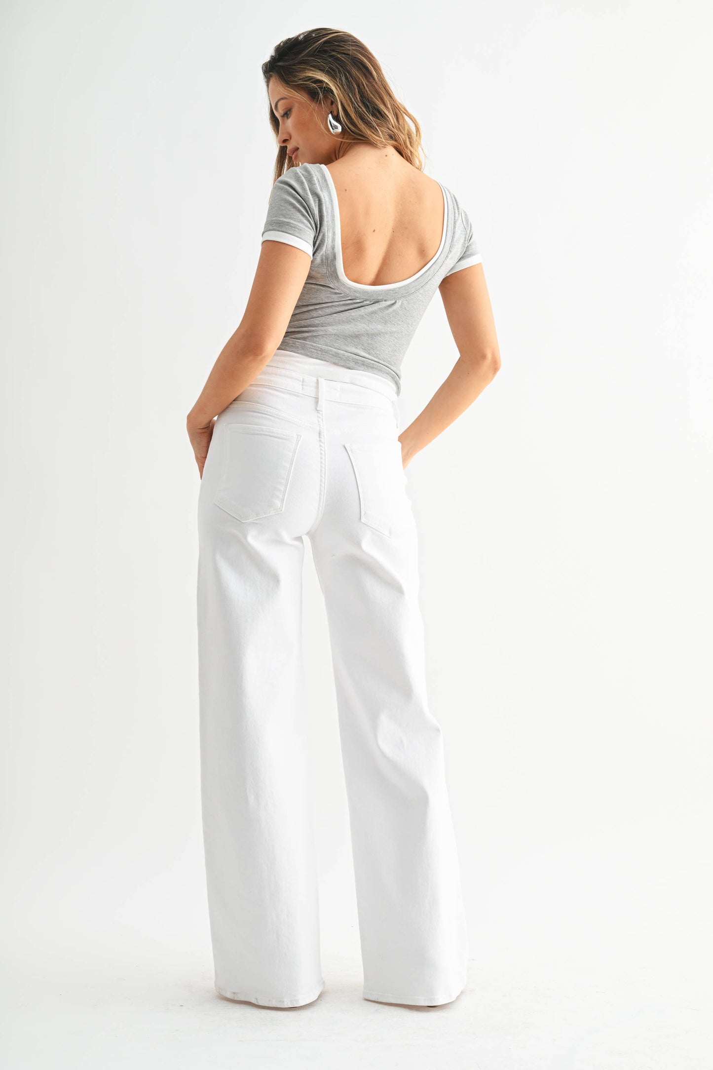 Woman wearing a gray top and white pants on a white background