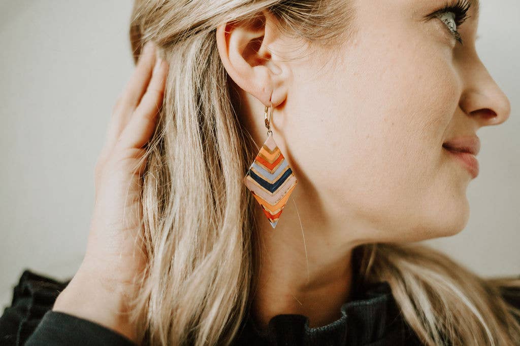 Close-up of a woman wearing colorful geometric earrings with a neutral background