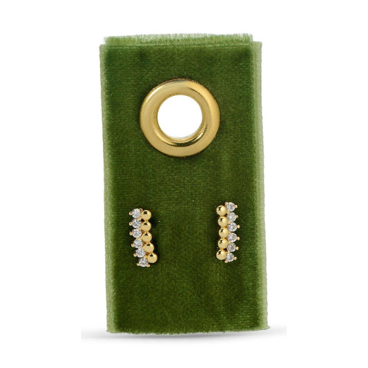 Gold and diamond earrings on a green velvet stand with a gold circular holder.