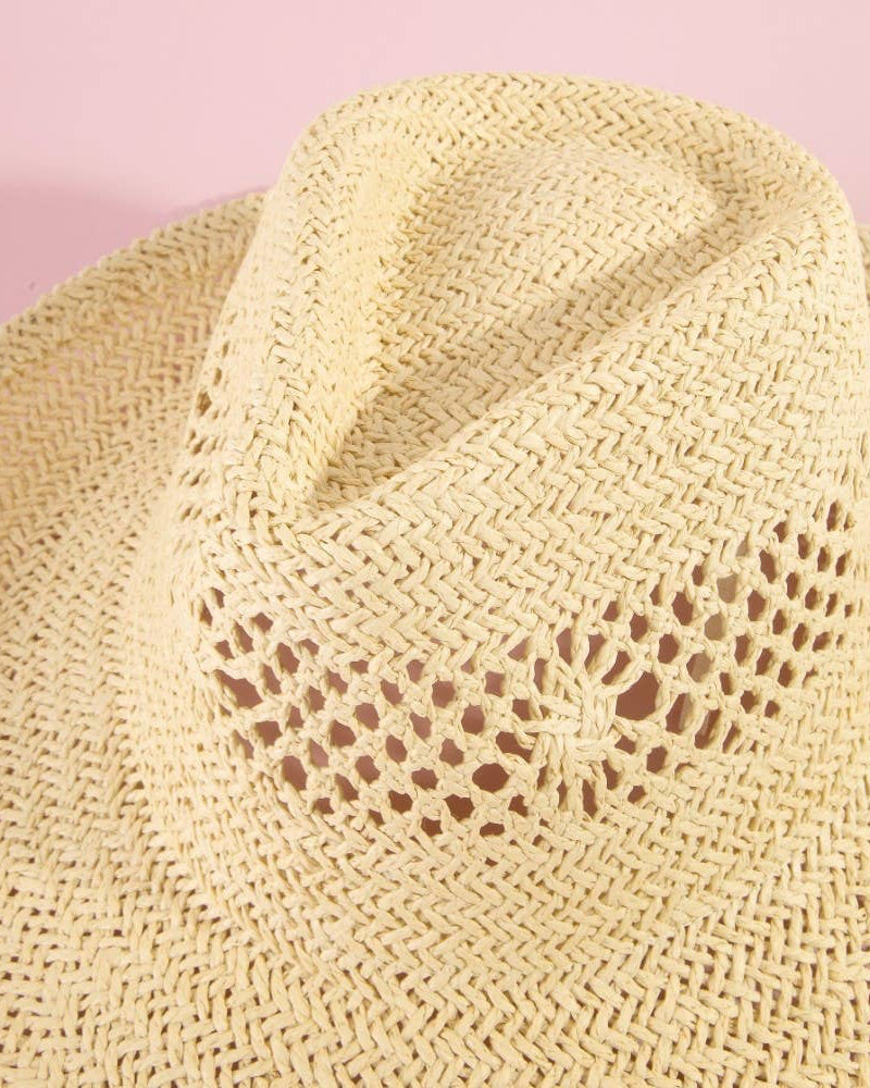 Close-up of a beige straw hat with a textured pattern on a pink background