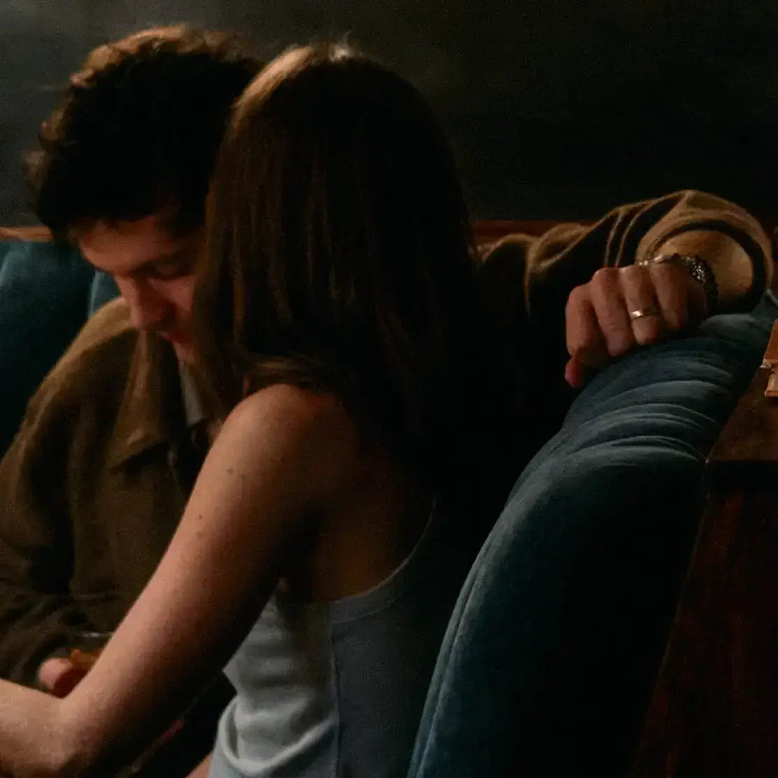 Two people sitting close together on a couch in a dimly lit room.