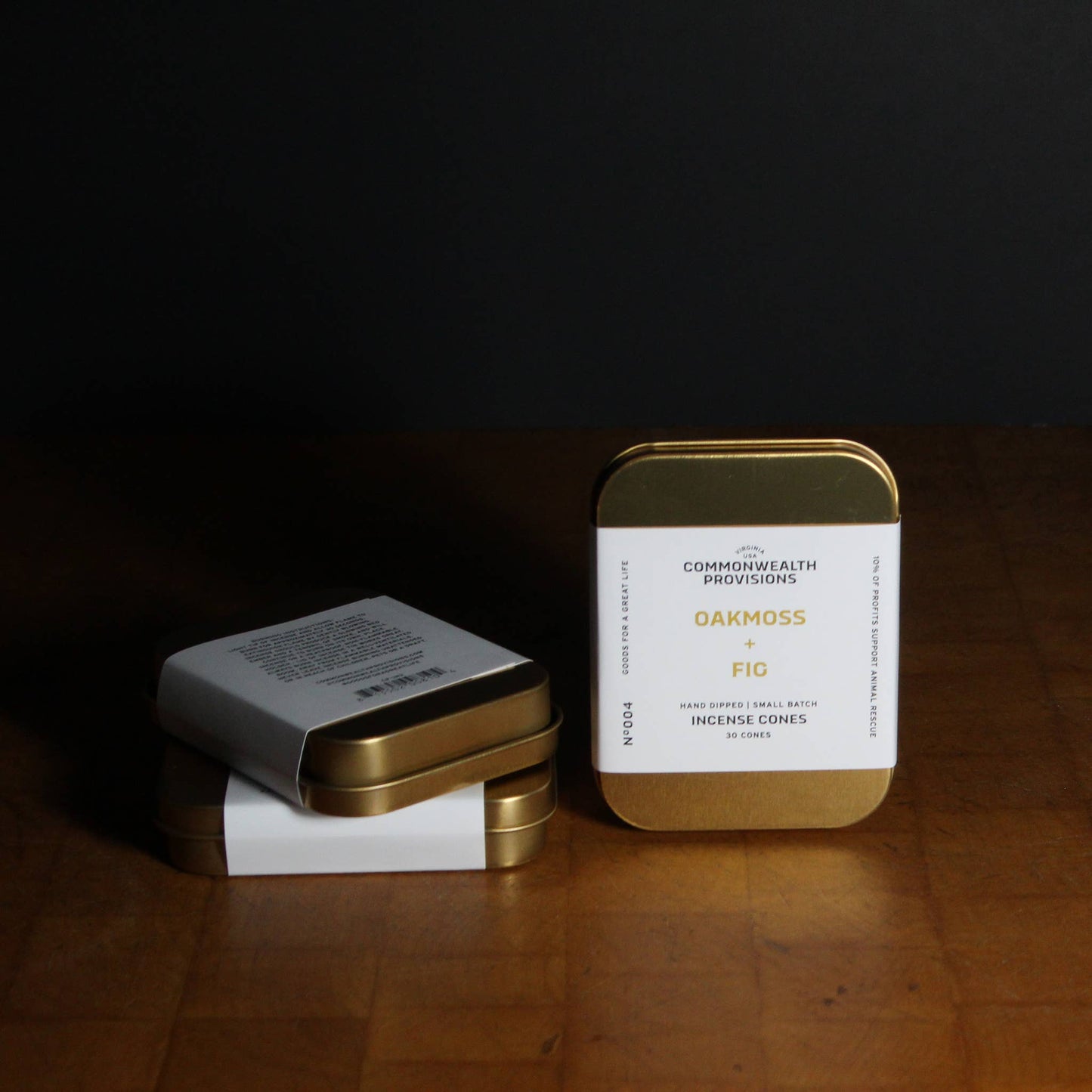Two tins with labels on a wooden surface against a dark background