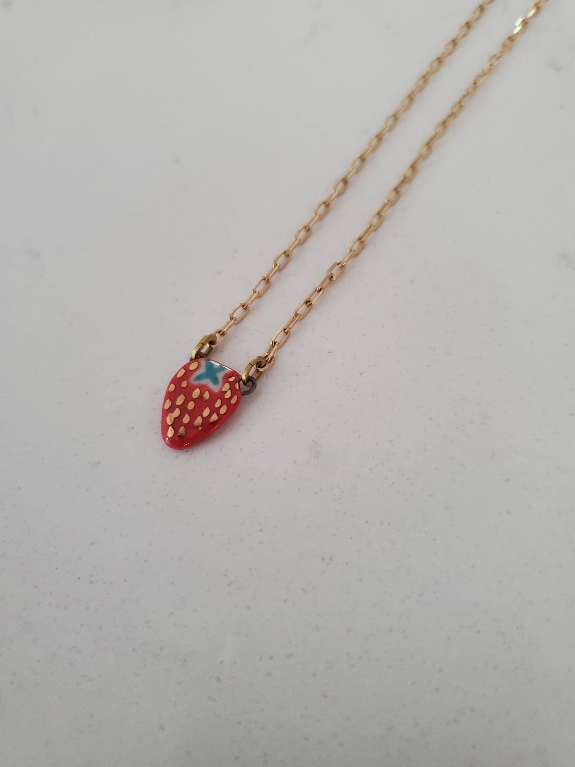 Necklace with a strawberry-shaped pendant on a light gray background