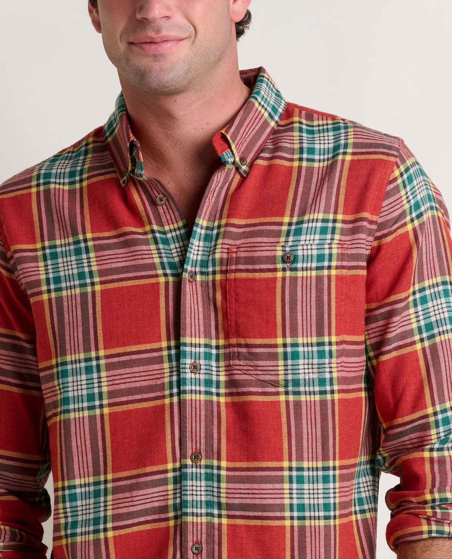 Man wearing a red and green plaid shirt against a plain background