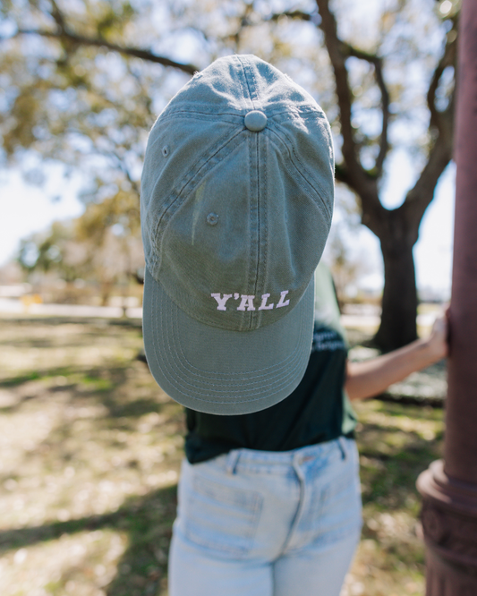 Person wearing a cap with 'Y'ALL' text outdoors