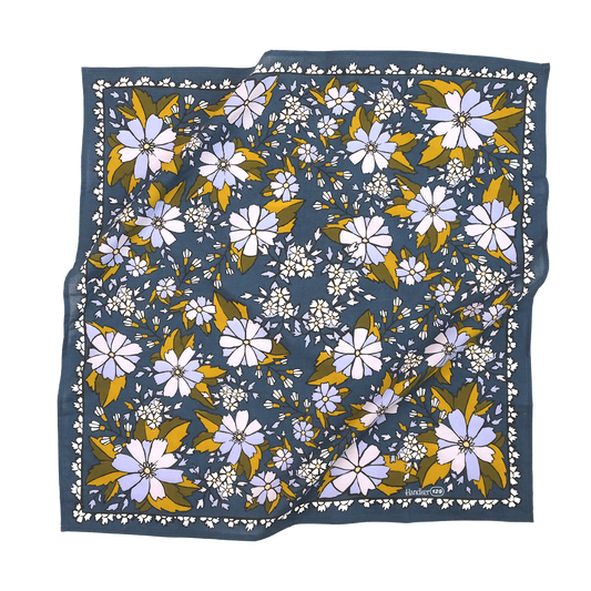 A square scarf with a navy blue background featuring a dense floral pattern of lavender, white, and mustard yellow flowers, with a white border.