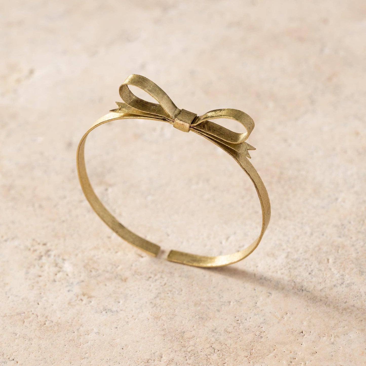 Gold bracelet with a bow design on a beige background